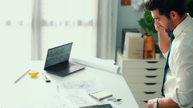 Architect engineer using laptop planning house design at office while sitting at meeting table with blueprint and equipment scatter around.Skilled civil engineer working at blueprint. Alimentation.