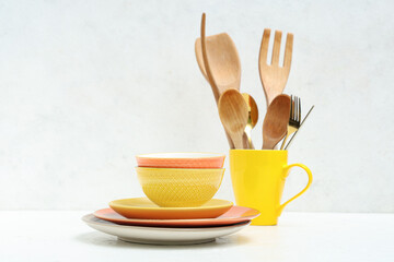 Stack of clean tableware and wooden cutlery on white background