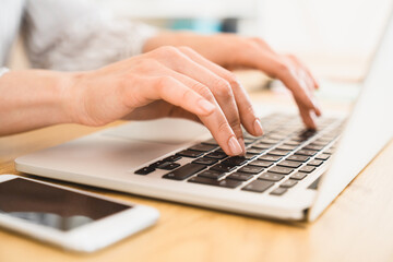 Close up cropped image of a keyboard while woman freelancer businessperson using typing on laptop,...