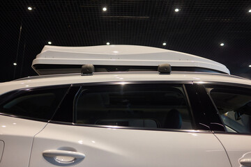 White vehicle with roof box, hood, grille, bumper and automotive lighting