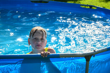 Child is taking a break from playing, relaxing in an above ground pool