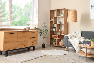 Modern interior of living room with black sofa, coffee table, shelving unit and chest of drawers