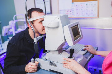 A young man at an oculist's appointment checks his vision with a modern microscope.