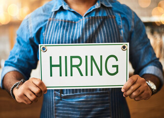 Coffee shop, hiring and hands with sign at cafe for small business, recruitment and job vacancy. Restaurant, store and closeup of waiter, barista and person for service, help and career opportunity