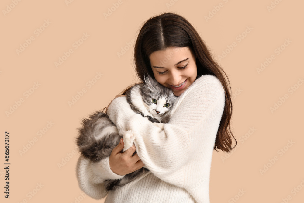 Wall mural Young woman with longhaired adorable cat on beige background