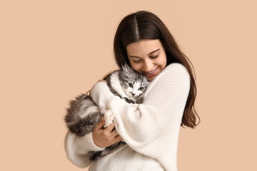 Obraz premium Young woman with longhaired adorable cat on beige background