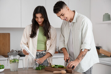 Happy young couple cutting fresh lime for mojito in kitchen