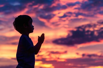 Fototapeta premium A young boy stands in front of a beautiful sunset, looking up at the colorful sky