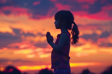 Fototapeta premium A young girl stands alone admiring the beautiful sunset