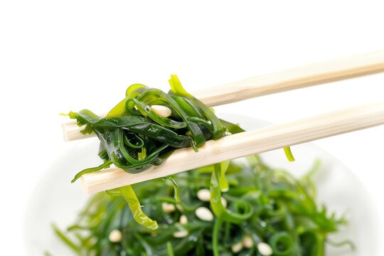 Chopsticks over chuka salad with seaweed on white background