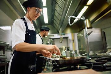 Female cook preparing food in kitchen.