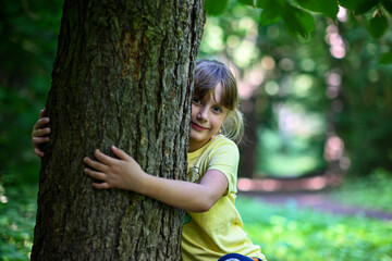 Young girl is embracing a large tree in a forest showing her love and connection to nature
