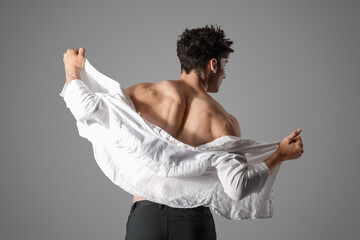 Muscular young man in white shirt on grey background, back view