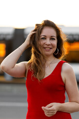 Happy self confident beautiful attractive sexy young woman in a red dress. Happiness, freedom, confidence. Sunset, summer