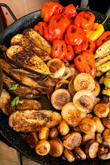 Assortment of fresh healthy vegetables on a BBQ grilling. Grilled vegetables: red paprika, zucchini, eggplant, mushrooms and onions served on a dish. Top view. Rustic style.