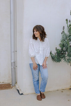 Smiling woman in casual outfit leaning against wall