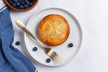 Mini blueberry pie on the plate and fresh blueberries , overhead view