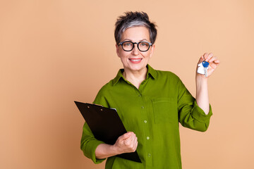 Photo portrait of lovely pensioner lady documents realtor sell house dressed stylish green garment isolated on beige color background