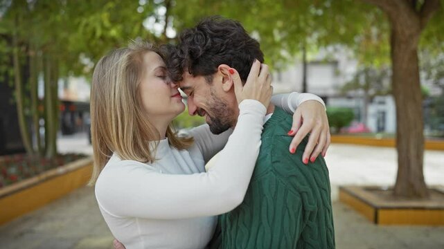 A loving couple embraces affectionately in a green lush park, embodying romance in an urban outdoor setting