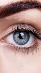 Obraz premium Detailed shot of eye during eyelash extensions on white background with copy space