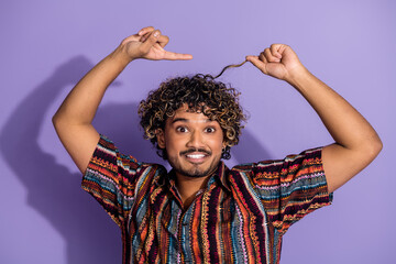 Photo of good mood man with beard wavy hairstyle dressed print shirt indicating at curl on head isolated on purple color background