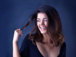 Hair, soft or laughing woman in studio for cosmetic, shine and shampoo results on blue background. Haircare, beauty and gen z model with smooth, texture or growth from scalp treatment or satisfaction