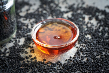 Black cumin or Nigella sativa seed oil in a bowl. Healthy nutritional supplement.