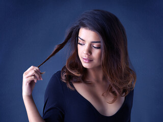 Fototapeta premium Hair, soft and woman in studio for cosmetic, shine and shampoo results on blue background. Haircare, beauty and gen z girl model with smooth, texture or growth from scalp treatment or satisfaction