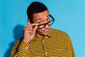 Photo portrait of handsome young guy annoyed touch specs dressed stylish plaid garment isolated on blue color background
