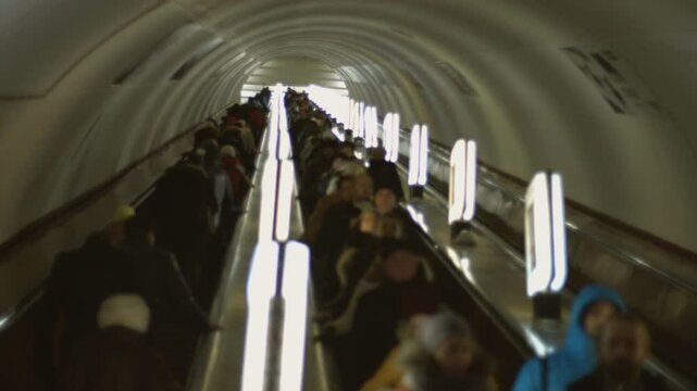 People go on the escalator. Passengers descend into the subway. Underground transport. Peak hour.