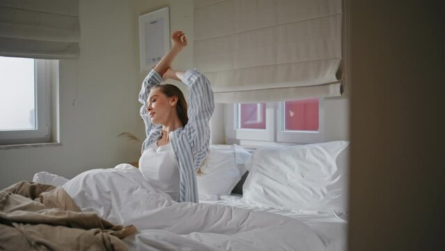 Domestic woman stretching body in bedroom at morning showcasing health vitality
