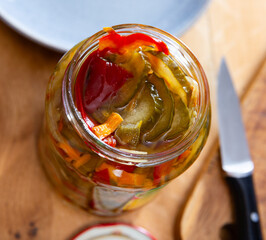 Overhead view of spicy homemade pickled cucumber salad wild bell peppers and carrots in open glass...