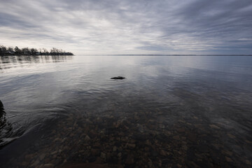 A serene scene of a lake with a dock under the sky in monochrome