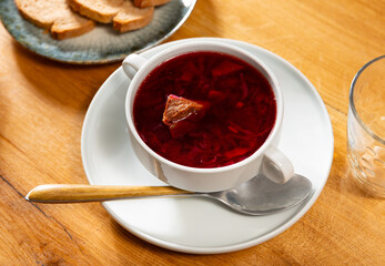 Just prepared borscht served in bowl with sour cream and bread