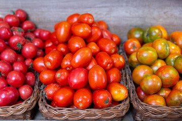 In warehouse of store - plastic boxes filled to top with ripe red tomatoes fruits. Gardening Products Wholesale Store. Store sells pink and red tomatoes, displayed in large boxes in shop window.