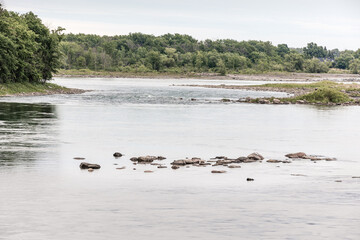 A scenic lake shoreline with rocky terrain and trees in the background