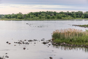 A scenic lake shoreline with rocky terrain and trees in the background