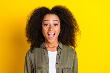 Photo of impressed crazy girl with perming coiffure wear khaki shirt astonished staring open mouth isolated on yellow color background