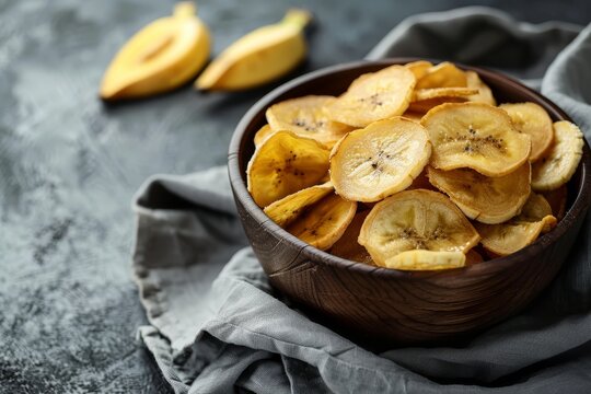 Home made healthy banana chips on a dark background focused