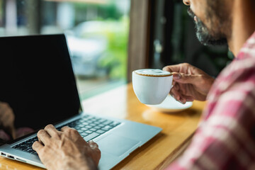 Young business man working on portable laptop computer in coffee shop.