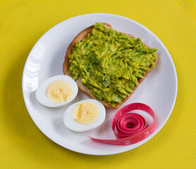 Food for weight loss. Egg, avocado, toast, meter. Cooking healthy food at home. Food on a yellow background.