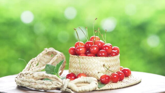 Red Cherry fruit in bamboo basket on on green bokeh background, Japanese Red highest variety of cherries on wooden table in the garden.