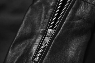 Texture of black leather jacket with zipper as background, top view