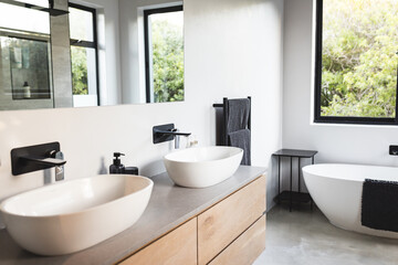 Modern bathroom with double sinks, wooden cabinets, and freestanding bathtub, copy space