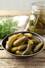 Pickled cucumbers in bowl on wooden table