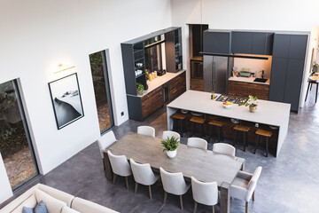 Modern kitchen and dining area with large table, chairs, and island counter, copy space