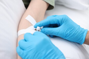 Nurse inserting IV into arm of patient in hospital, closeup