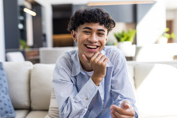 Smiling teenage boy sitting on couch at home, looking relaxed and happy © wavebreak3
