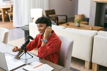 Recording podcast, young man using microphone and laptop in home office
