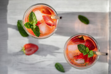Summer refreshing homemade cocktail with strawberries and mint on the table in a bright kitchen